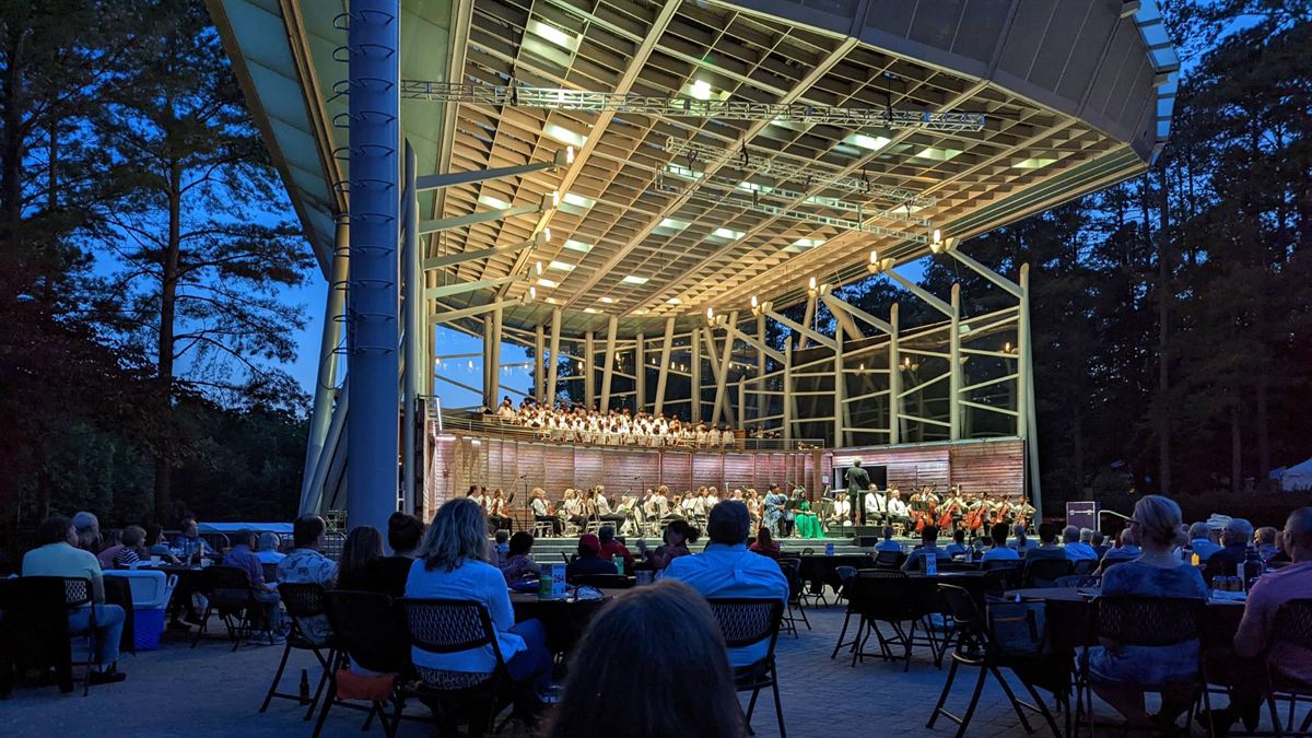 An outdoor amphitheater lit up at dusk for a symphony concert